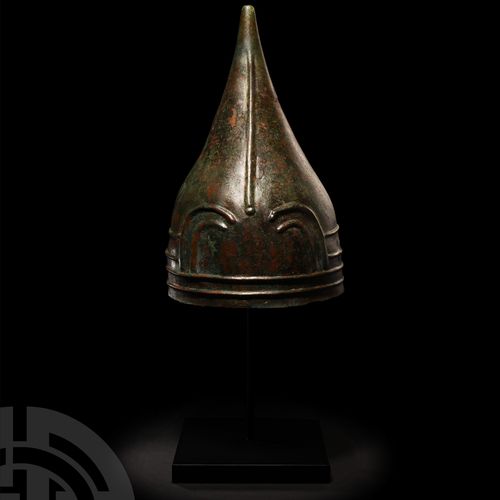 Null 乌拉尔式蛇形头盔。公元前8-7世纪，一个宽大的圆锥形青铜头盔，由一块金属板锤炼而成，正面有一个凸起的抽象线性图案，帽檐上方有四条环形肋骨，正面的拱形肋&hellip;