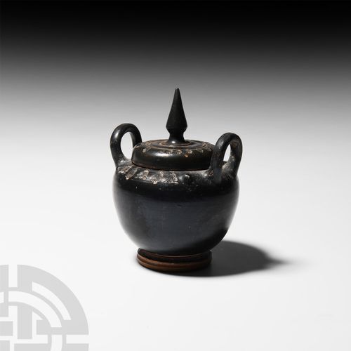 Null 希腊黑釉罐，公元前5-3世纪 一个黑釉罐，蹲着身子，宽大的肩部印有风格化的花藤，两个圆形截面的把手和盘状的脚；盖子上有圆锥形的顶盖和印有贝壳的图案。 &hellip;