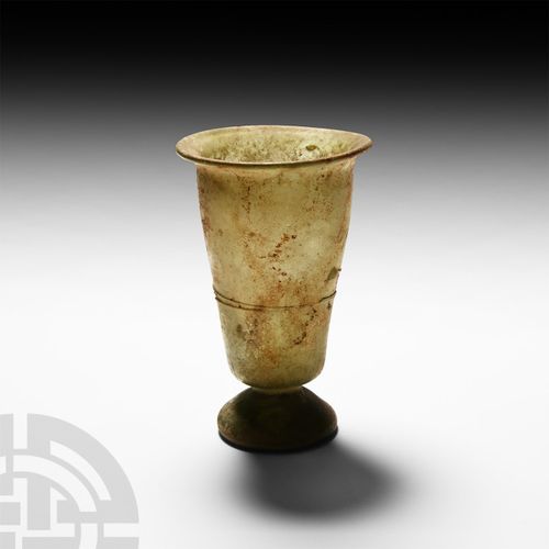 Null 罗马玻璃有脚烧杯，公元4-5世纪 绿色玻璃烧杯，由缓缓变细的U型杯身和更凸出的杯身组成，圆弧形的边缘和圆顶的底，装饰性的应用痕迹到赤道。参照康宁玻璃博&hellip;