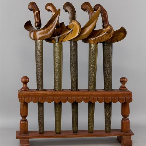 Null 五个木雕手柄的克里塞，装饰有风格化的图案，都有雕刻的铜套，放在木架上，印度尼西亚爪哇（B）。

支架：高56 x 宽43厘米，长：49 - 50厘米。