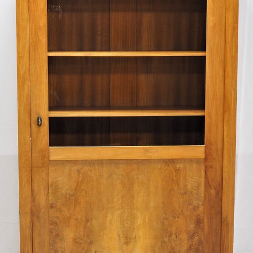 Bookcase, 30s 书柜，30年代

由木材制成，白蜡木，部分实心和贴面。直立的柜体，有向外弯曲的腿。下部有填充门，上部有玻璃门。里面有5个可调节的架子&hellip;