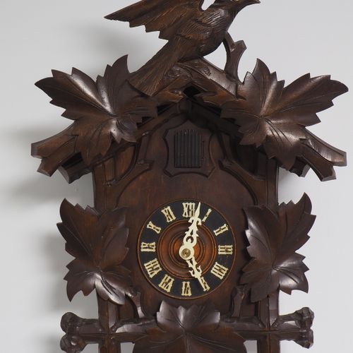 Cuckoo clock around 1900 1900年左右的布谷鸟钟

带屋檐的木箱，正面有雕刻的树叶。布谷鸟坐在顶部。黄铜板机芯，带链式升降机和两个砝码&hellip;