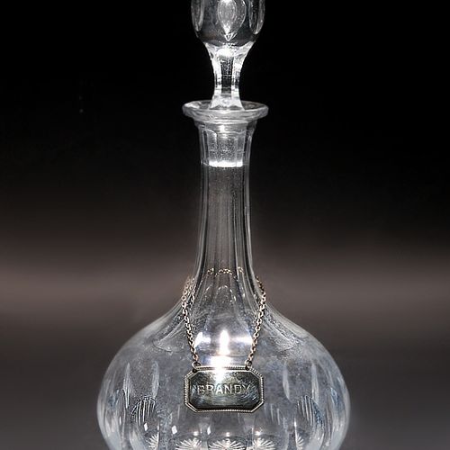 Karaffe 彩色玻璃，切割装饰，切割的瓶塞有穿透的气泡。高31.5厘米。脖子上有一条镀银金属吊坠的链条，上面写着 "BRANDY"。