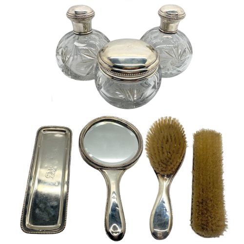 Null 西班牙银质打孔和切割玻璃的厕所套装，包括两个刷子，一个托盘，一个手镜，两个壶和一个紧凑型，20世纪下半叶。

最大。最大：24.5厘米。