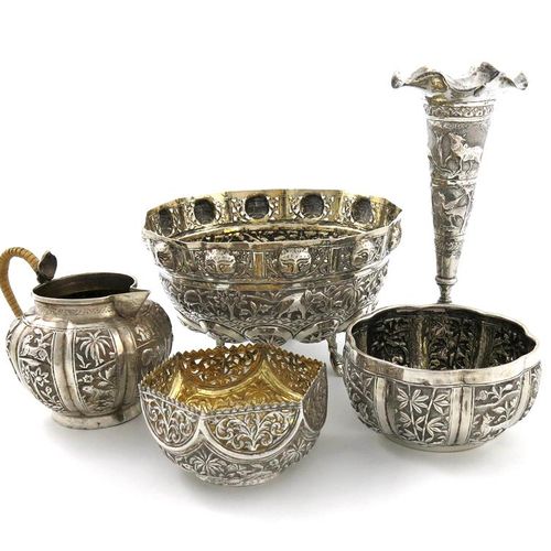 Null 一批混合的印度银制品，包括：一个圆盘形的碗，上面压印着大象和动物的叶子，边上有穿孔和面具的装饰，有四个脚，还有一个奶油壶，两个碗和一个花瓶，大约重23&hellip;