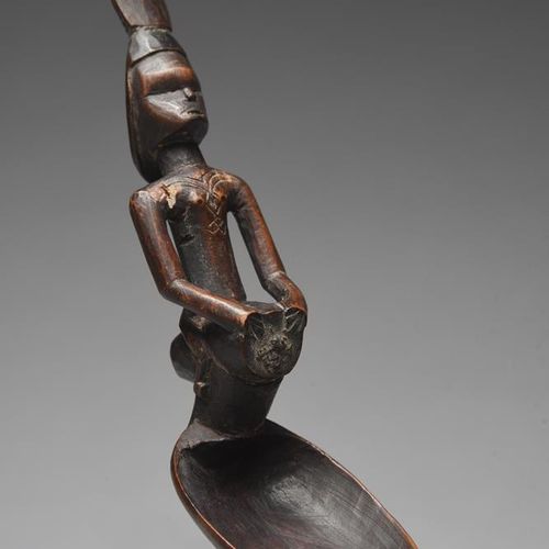 Null 刚果民主共和国的一个贝贝勺，柄部雕刻成一个骑在鼓上的人物，躯干上有疤痕和高大的头饰，长18厘米。