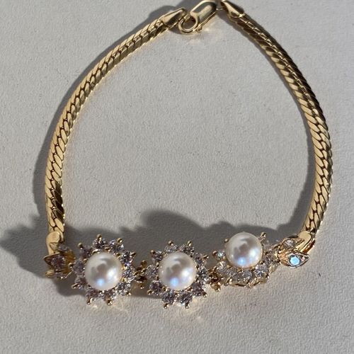Un bracelet en or jaune 18k 750 ml ornée de 3 perles à entourage de pierres blan&hellip;