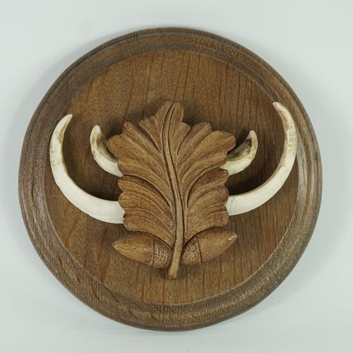 Null 砂岩和野猪獠牙放在木质底座上，中间装饰有橡树叶和橡子。