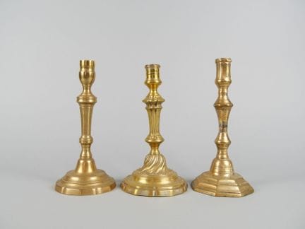 Three gilded metal candlesticks or torches in the 