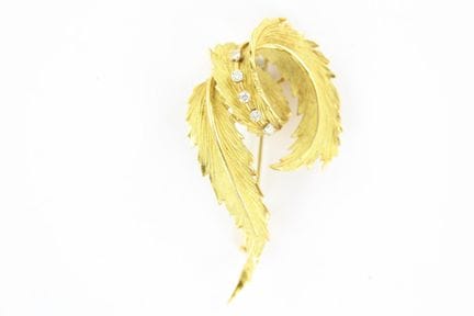 An 18K yellow gold brooch featuring a leaf design 