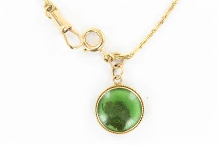 An 18K yellow gold watch chain featuring a charm a