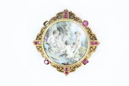 An 18K yellow gold brooch featuring putti on porce
