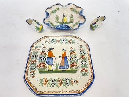 亨里奥（HENRIOT），产自坎佩尔。一件多色釉陶餐垫和一对（有裂纹）木屐，饰有布列塔尼夫妇图案。宽