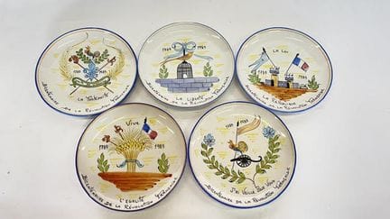 一套五只边缘素面的圆形多色釉陶盘，饰有革命性的图案。约1989年。直径：26厘米。