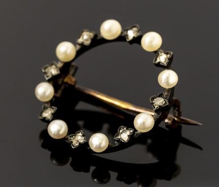 A round 750‰ gold brooch set with eight pearls and