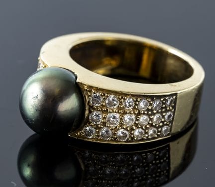 A wide 750% yellow gold ring set with a gray pearl