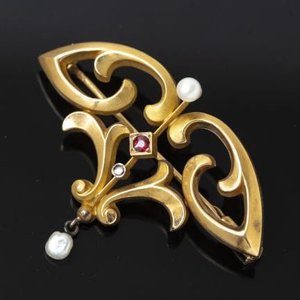 A 750‰ openwork gold brooch with two small pearls.