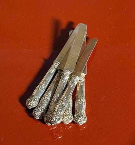 六把甜点刀，刀身采用镀金银材质，刀柄为银质，饰有带字母缩写的叶纹图案（有磨损）
毛重：279 克


