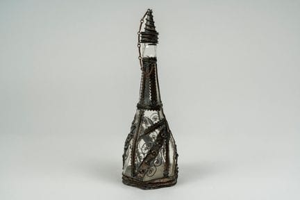 Botella con tapón de vidrio incoloro y base hexago