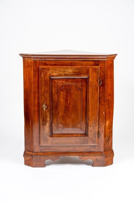 Single-door paneled corner cabinet with carved bra