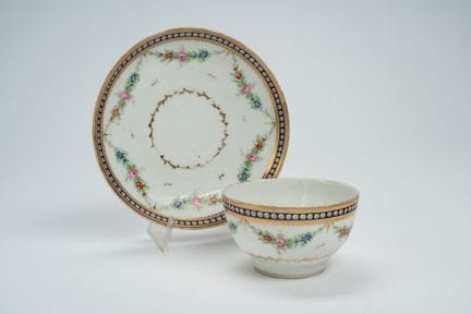 Taza y platillo de porcelana con decoración policr