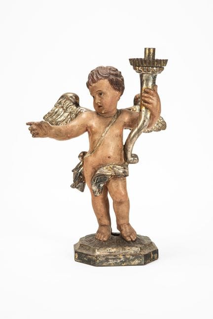 A carved and painted wooden cherub holding a torch