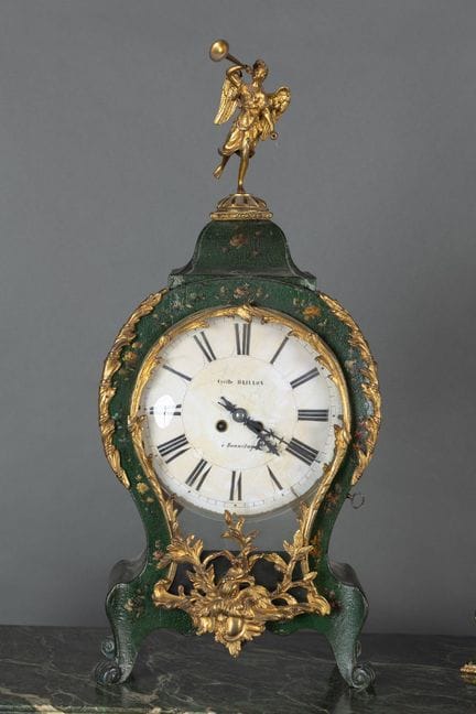 A clock with a lacquered wooden base decorated wit