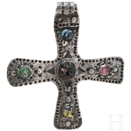 A silver cross-shaped pendant with punched decorat