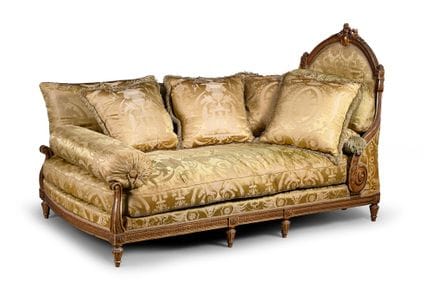 A wooden daybed with molded, carved, and gilded pa
