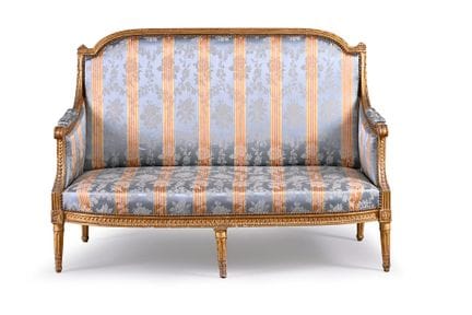 A wooden sofa with molded, carved, and gilded deta