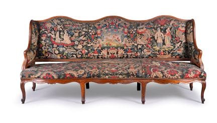 A wingback sofa in molded and carved walnut; the t