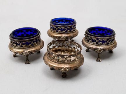 Set aus vier silbernen Salzstreuern auf drei Füßen