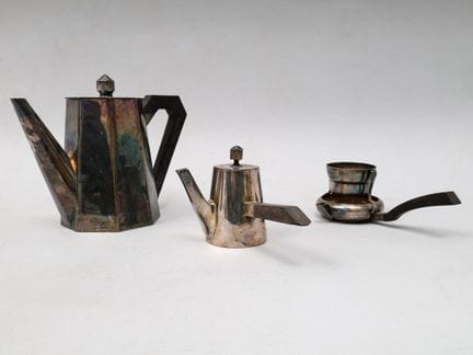 Tetera, colador de té y jarrita de metal plateado,