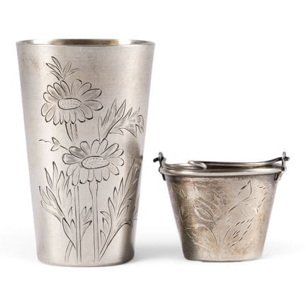 A SILVER BEAKER AND TEA STRAINER WITH ENGRAVED FLO