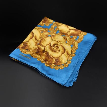 CHANEL 
Turquoise silk scarf with a gold camellia 