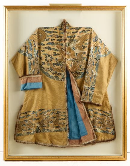 中国清代冬季朝服或吉服，黄丝绸刺绣。图案描绘了生动的龙在流水波涛、山峦和缕缕白云间追逐珍珠的场景。以