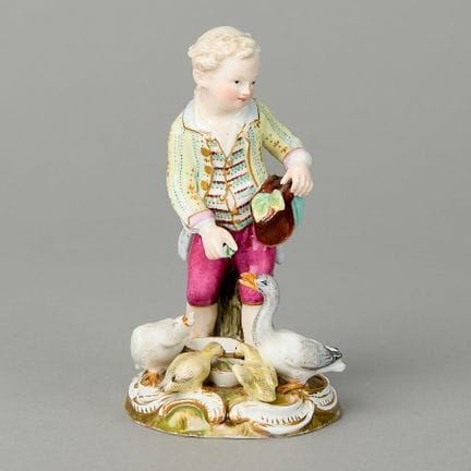 Meissen, Germany. Porcelain figure of a boy feedin