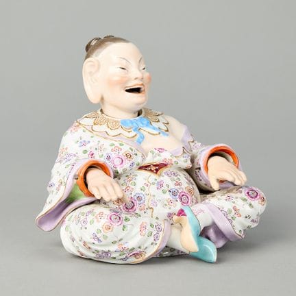 德国迈森。一座点头宝塔的瓷质小雕像。雕像双腿交叉，嘴巴张开露出灿烂笑容，舌头可活动并上下摆动，头部和