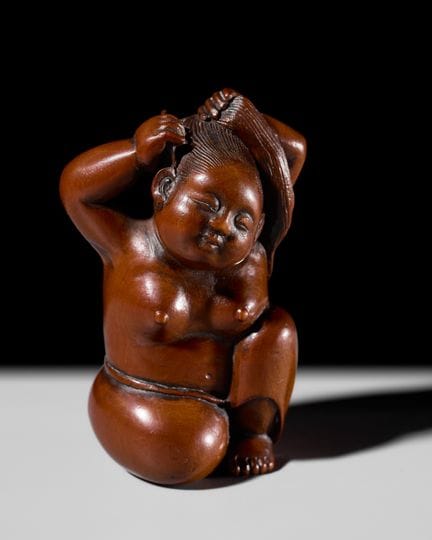 “法实”：一件精美且尺寸宏大的木制根付，刻画了一位正在束发的女子
作者：明庆斎法实，署名“法实”

