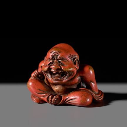 UN RARO NETSUKE LACADO EN ROJO QUE REPRESENTA A UN
