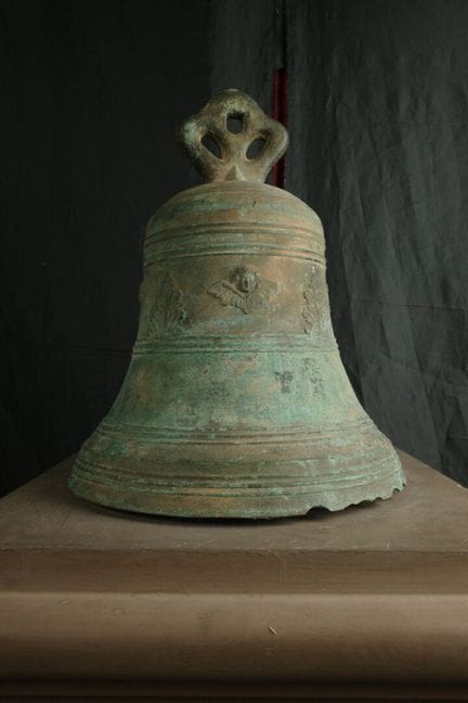 Importante campana in bronzo decorata con teste d’