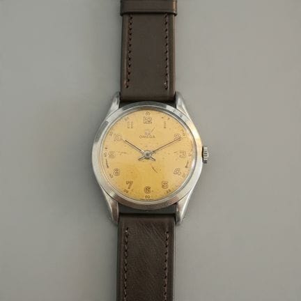 欧米茄，约1950年，型号30T2
这款腕表采用圆形不锈钢表壳，香槟色表盘，时标为阿拉伯数字时标。搭