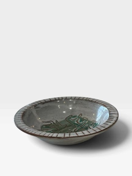 让·里维耶（1915-2017）
白色和绿色釉面陶瓷翅形杯，饰有自由风格的雕刻图案。
器底有签名。
