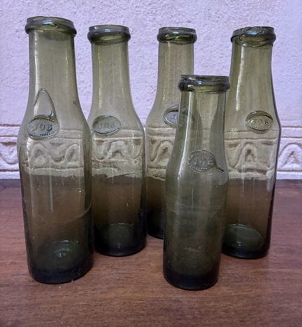 Suite de 5 bouteilles en verre soufflé flanquées d