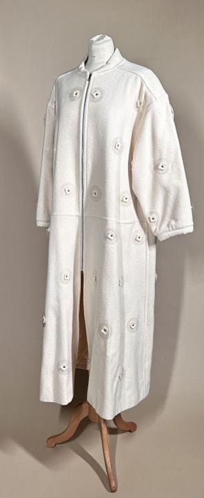 COURRÈGES 巴黎 
奶油色羊毛长大衣，饰有固定在透明亚克力圆盘上的拼接片，拉链开合，长袖，两