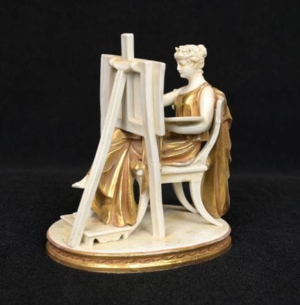 一件部分镀金的瓷器摆件，描绘了一位正在作画的古风女子（镀金处有轻微磨损）。卡波迪蒙特，19世纪。高：