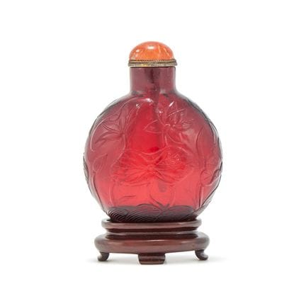 Y 一件中国雕花红玉玻璃鼻烟壶，19世纪，壶身环绕雕刻着一幅连贯的荷塘图景，配珊瑚壶塞，高7.7厘米