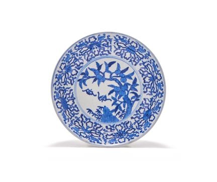 一件中国青花盘，盘面绘有佛教八宝图，中央饰有两只飞蝠在结果的桃树下，盘底刻有六字“大庆乾隆年制”款，