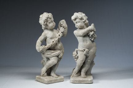 A pair of composite stone garden sculptures depict