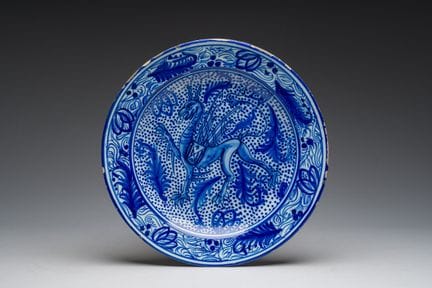 一件大型西班牙蓝白马约利卡瓷盘，盘面饰有神话中的动物，周围环绕着花卉图案，产自马尼塞斯，18/19世
